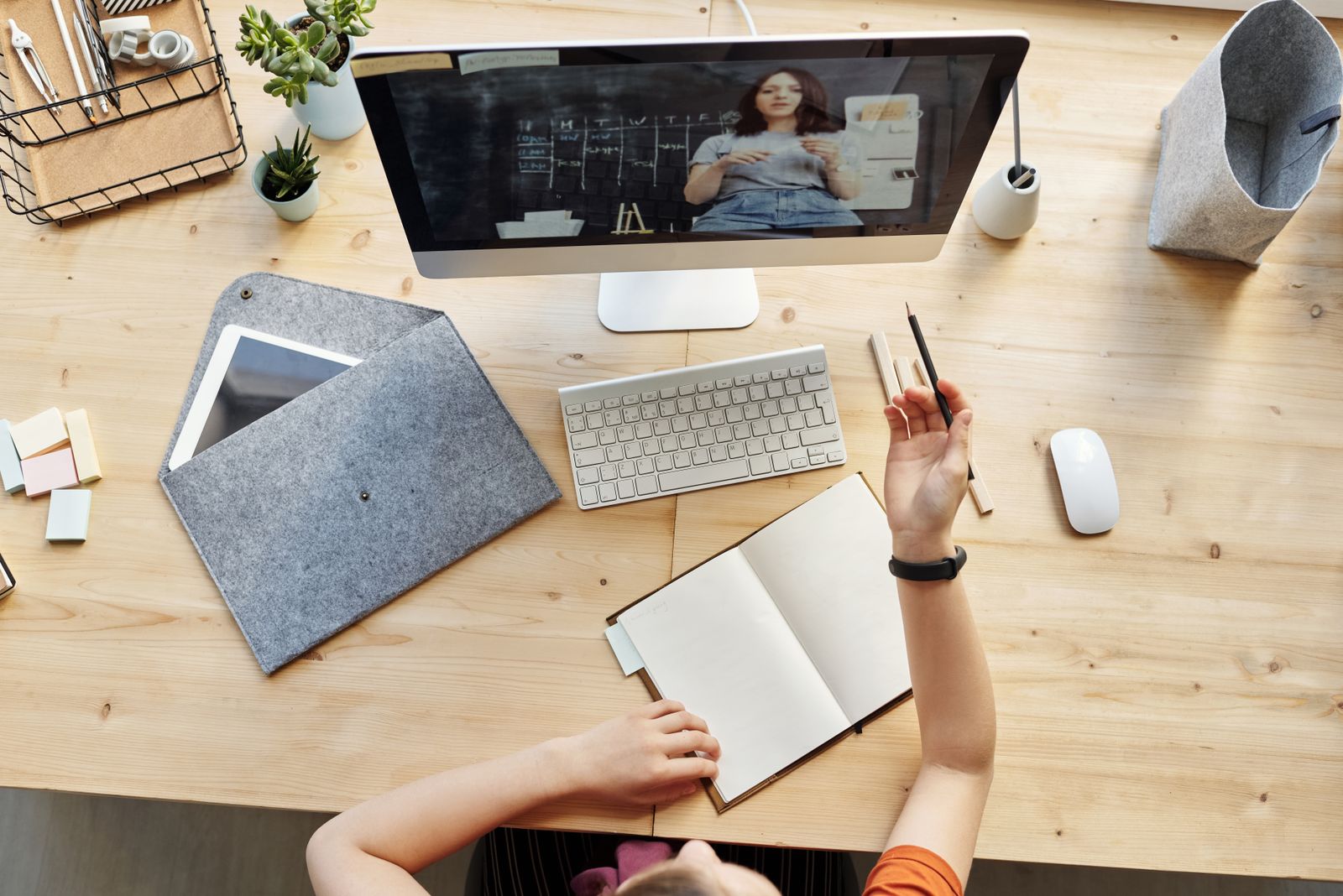 An open notebook and pen beside a laptop showing an online Portuguese lesson